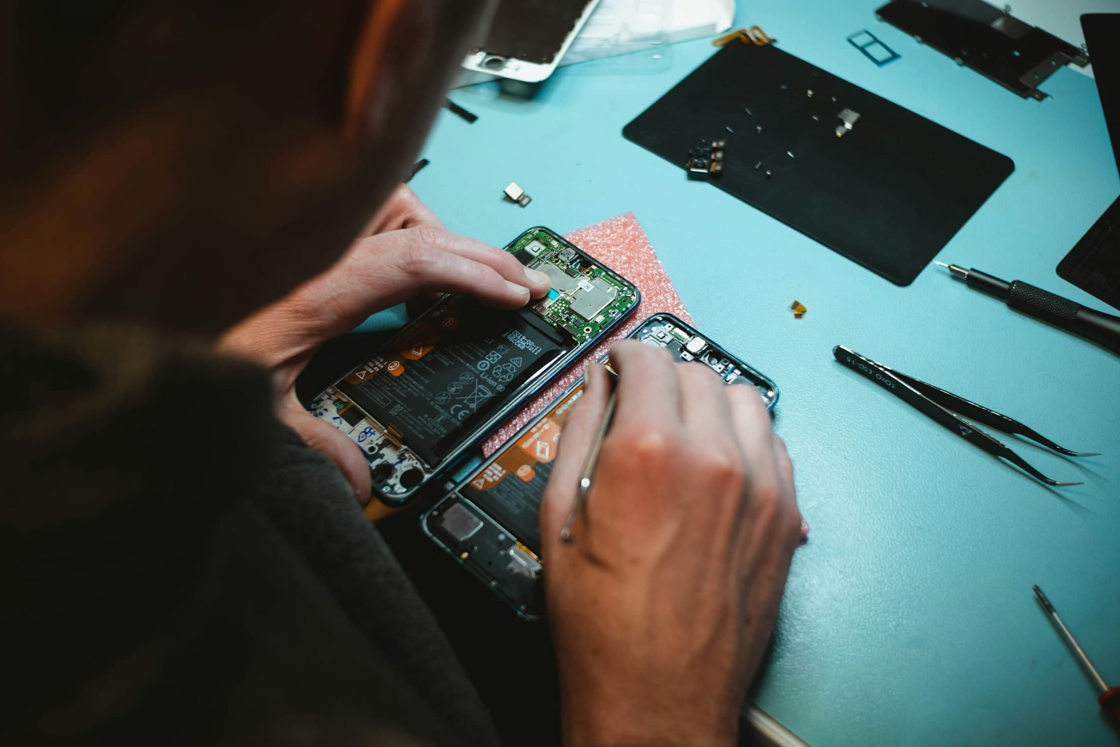 Technician replacing parts inside an opened smartphone